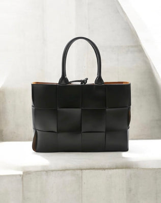 Petra Flettet Taske i Kalveskind - Eksklusiv sort flettet læderhandtaske med bredt vævet mønster og dobbelte håndtag. Rektangulær form med cognacfarvet indvendigt læder. Moderne og elegant design perfekt til hverdag og fest. Alle produkter, Tasker, Bestsellers, Nyheder, New products, Bestsellers 2, Petra, Flettede tasker, Tasker i ægte læder