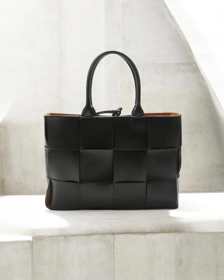 Petra Flettet Taske i Kalveskind - Eksklusiv sort flettet læderhandtaske med bredt vævet mønster og dobbelte håndtag. Rektangulær form med cognacfarvet indvendigt læder. Moderne og elegant design perfekt til hverdag og fest. Alle produkter, Tasker, Bestsellers, Nyheder, New products, Bestsellers 2, Petra, Flettede tasker, Tasker i ægte læder